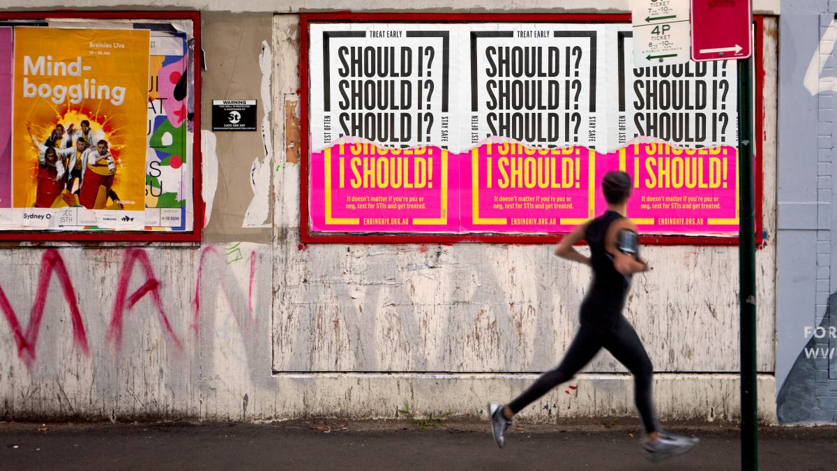 Person running past ACON STI Testing and Treatment posters