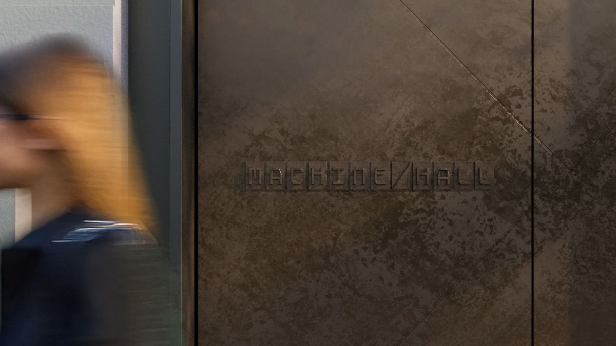 Woman walking past outdoor Machine Hall signage