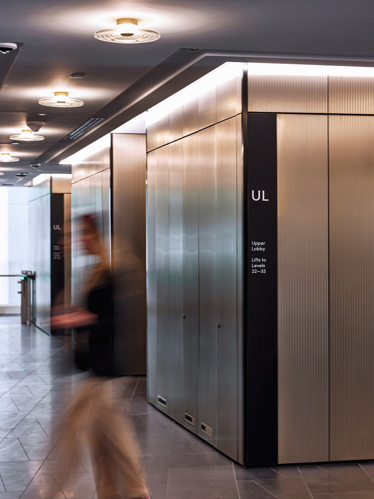 Person walking past elevator inside Quay Quarter building