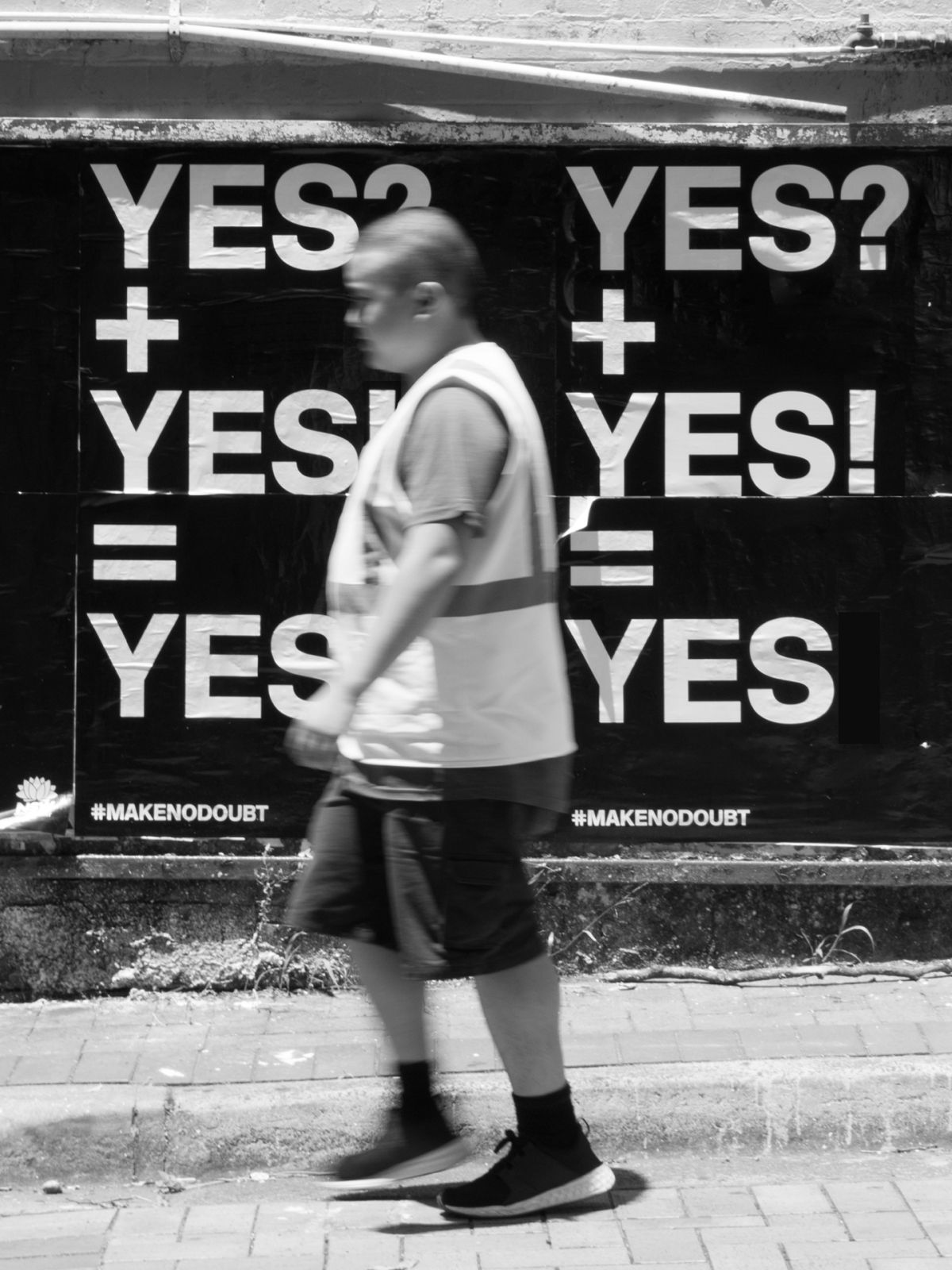 Man walking infront of YES campaign bill poster