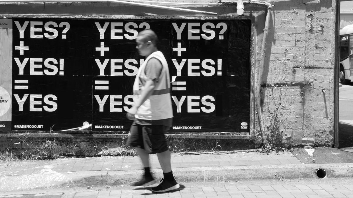 Man walking infront of YES campaign bill poster